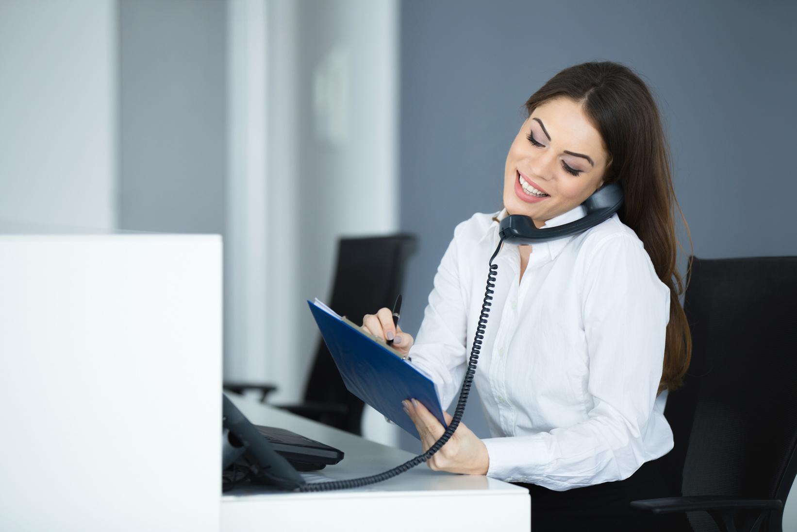 Young happy secretary talking on the phone.